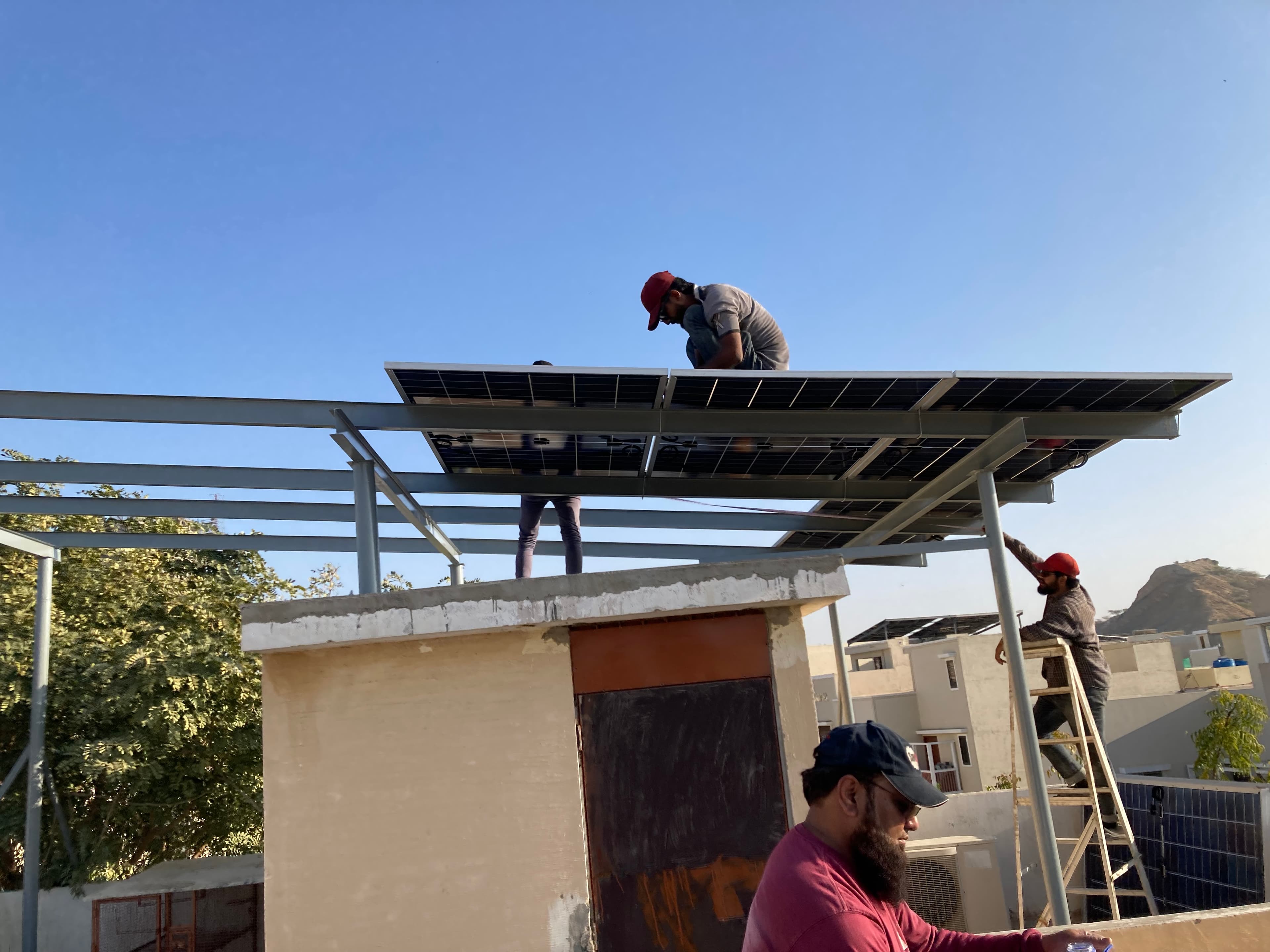 Crew mounting solar panels onto a rooftop steel frame in Karachi.