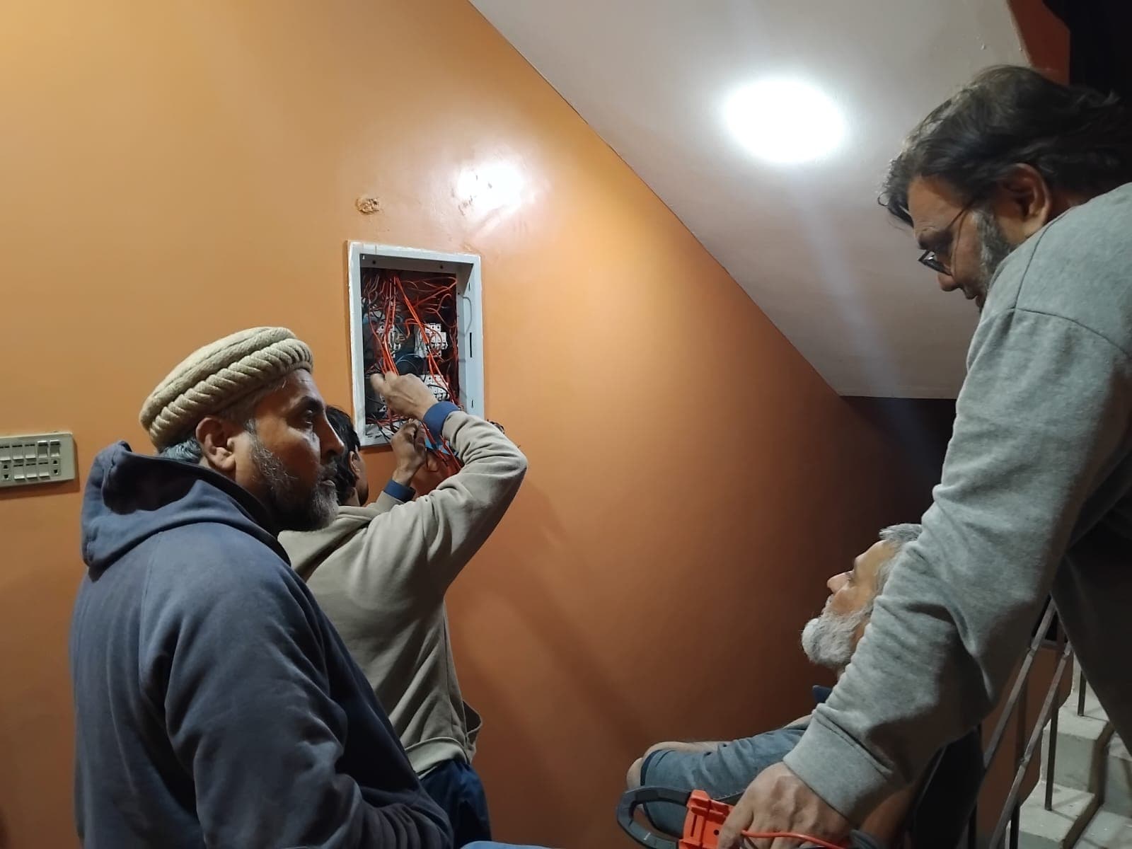 Crew checking a wall-mounted distribution board during solar commissioning.